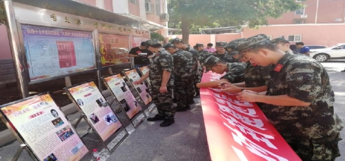 武警官兵认真观看反邪教展牌，并在反邪教横幅上签字