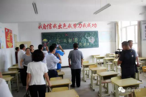 与会人员参观第四中学反邪教黑板报